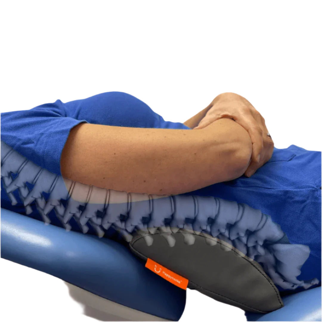 A person lying back on a dental chair with the Happynecks® Pillow placed under their lower back. The image includes a superimposed visualization of the spinal alignment, showing how the pillow supports the lumbar region to ensure proper posture and comfort during dental procedures.