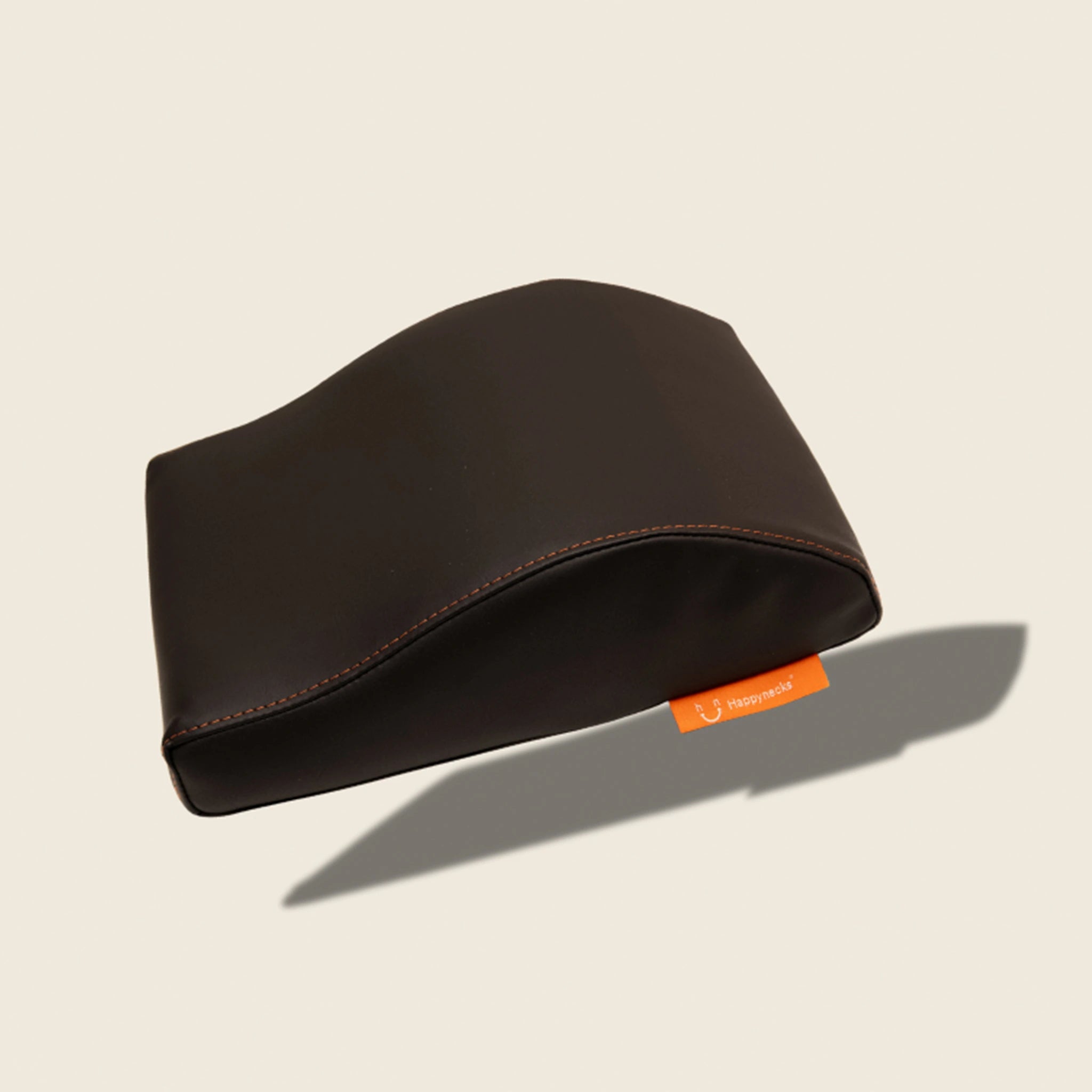 A sleek black ergonomic support cushion with subtle orange stitching and a brand tag, designed for comfort during long sessions. Over white background.