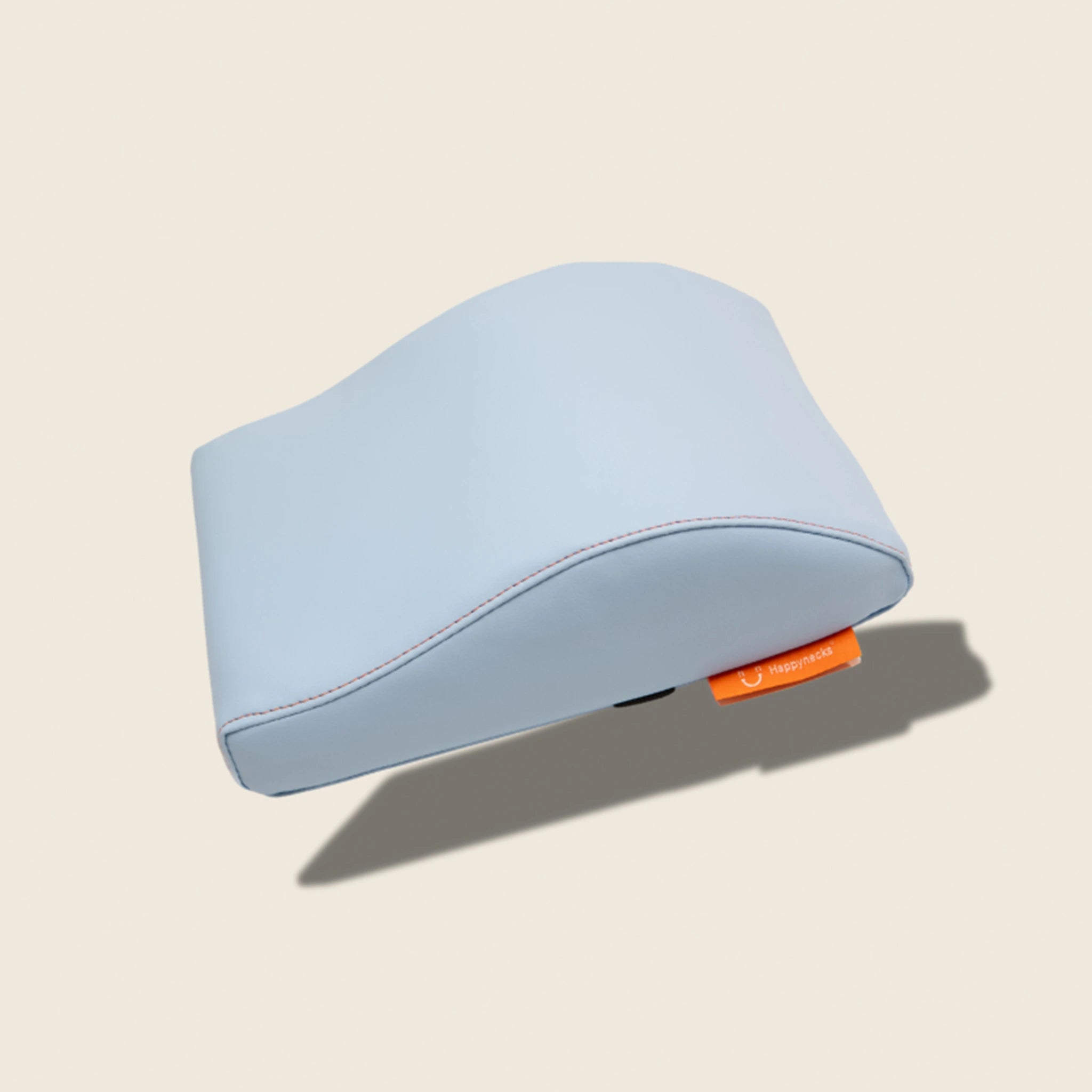 A dolphin-blue ergonomic cushion with a smooth surface, highlighted by orange stitching and a brand tag. Over white background.