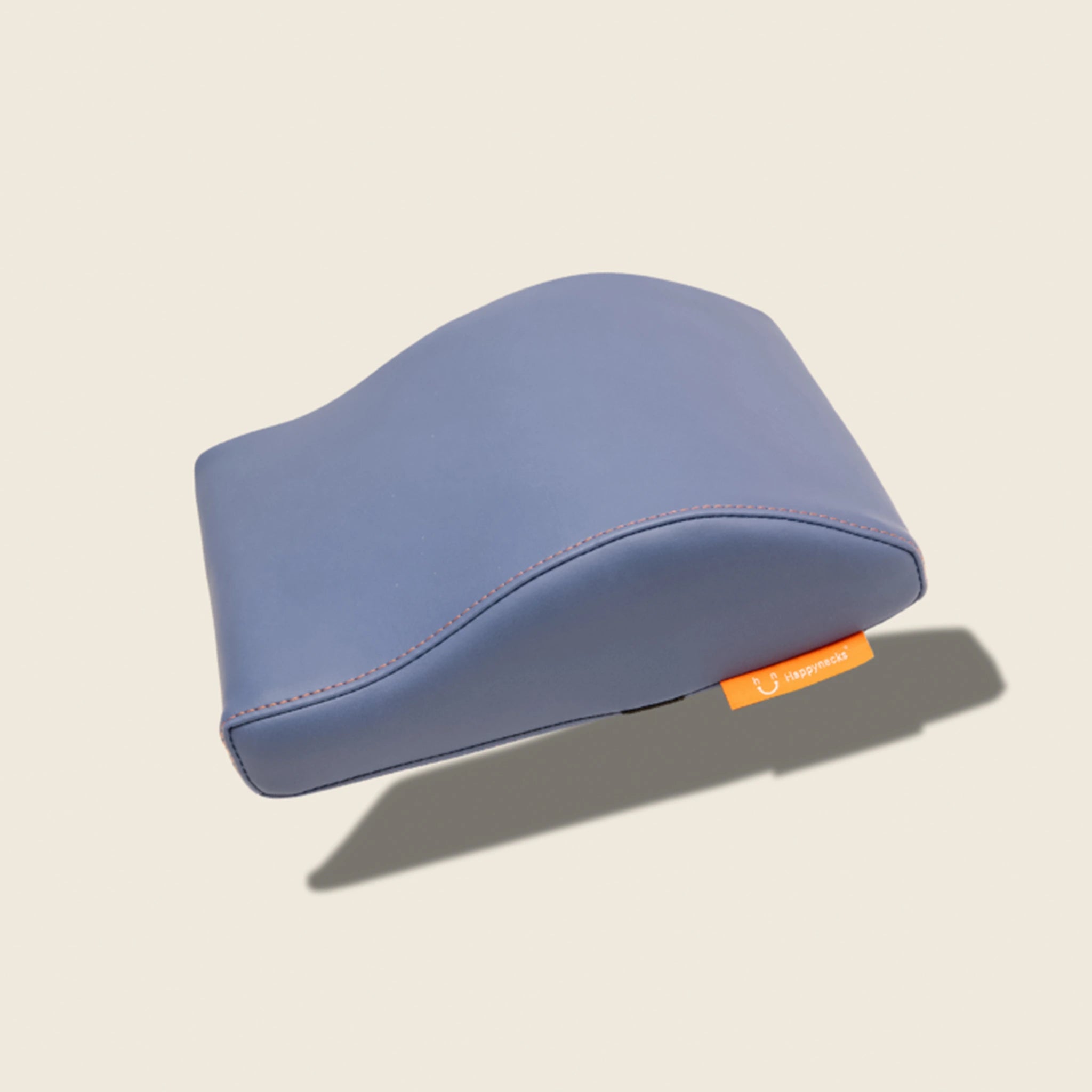 A sky-blue ergonomic cushion with a smooth surface, highlighted by orange stitching and a brand tag. Over white background.